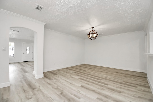 spare room featuring crown molding, light wood-type flooring, and a textured ceiling