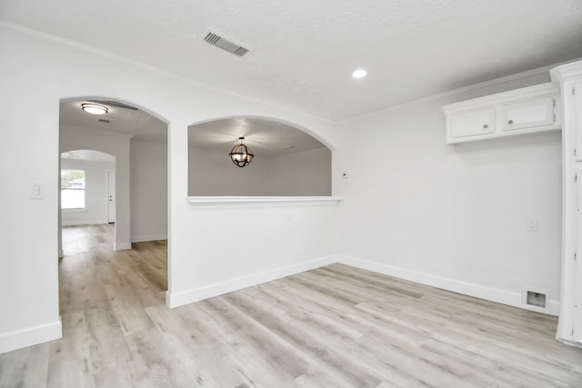 unfurnished room with a textured ceiling and light hardwood / wood-style floors