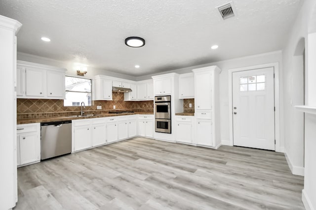 kitchen with white cabinetry, a healthy amount of sunlight, light wood-type flooring, and appliances with stainless steel finishes