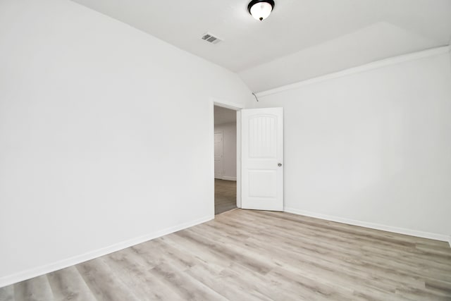 spare room featuring vaulted ceiling and light hardwood / wood-style flooring