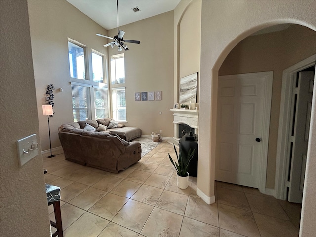 living room with ceiling fan, a towering ceiling, and light tile patterned floors