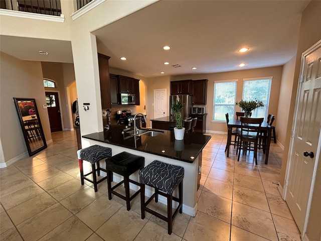 kitchen with sink, appliances with stainless steel finishes, dark brown cabinets, kitchen peninsula, and a breakfast bar area