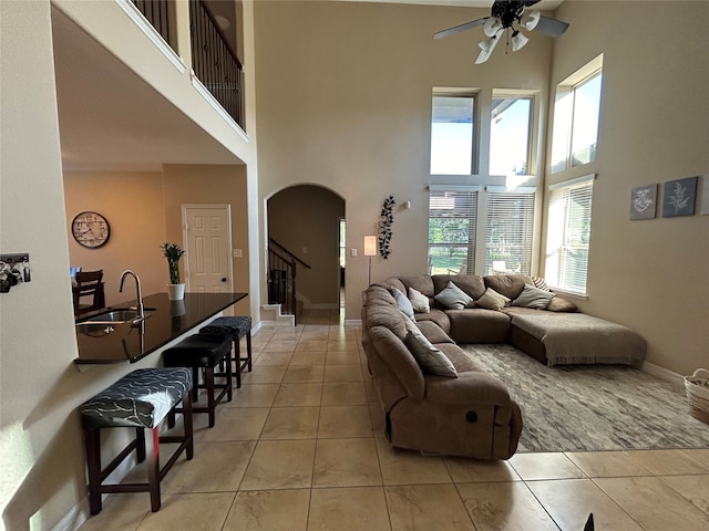 living room with ceiling fan, light tile patterned floors, sink, and a high ceiling