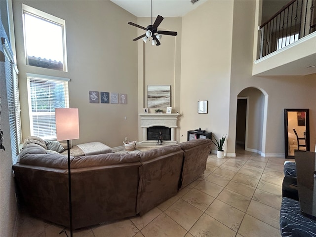 tiled living room with ceiling fan and a high ceiling