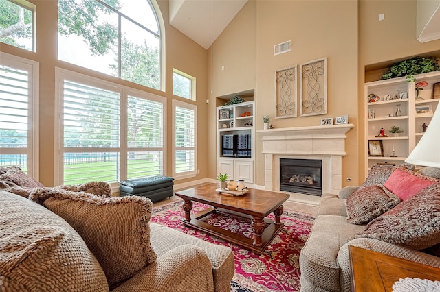 living room featuring a healthy amount of sunlight, built in features, a fireplace, and a high ceiling