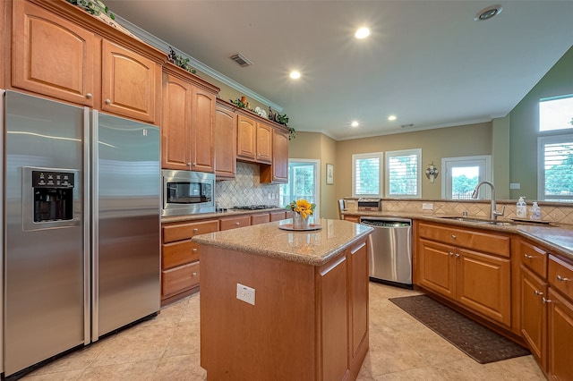 kitchen with sink, crown molding, decorative backsplash, appliances with stainless steel finishes, and a kitchen island