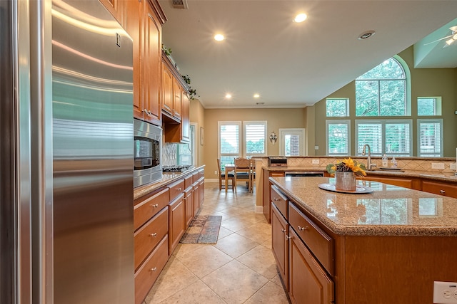 kitchen with light stone countertops, plenty of natural light, a kitchen island, and appliances with stainless steel finishes