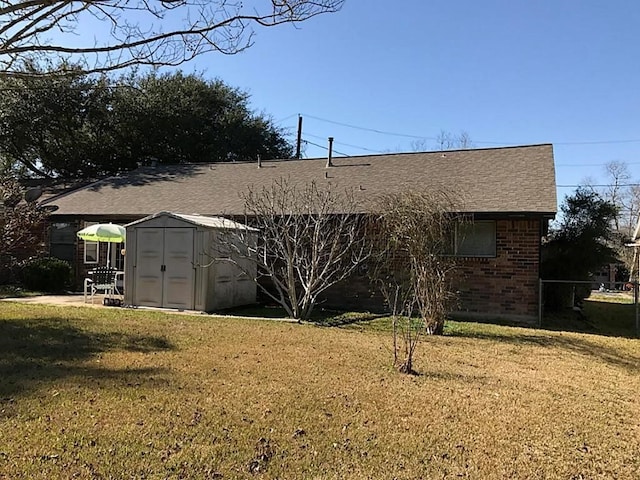 back of property with a storage unit and a yard