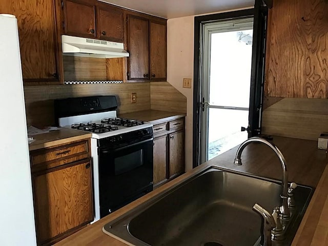 kitchen featuring decorative backsplash, white appliances, sink, and a wealth of natural light