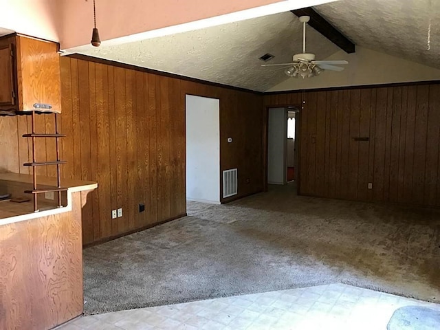 carpeted empty room with lofted ceiling with beams, ceiling fan, and wood walls