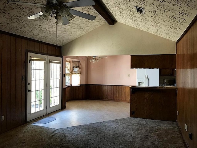 interior space featuring ceiling fan, white refrigerator with ice dispenser, and wooden walls