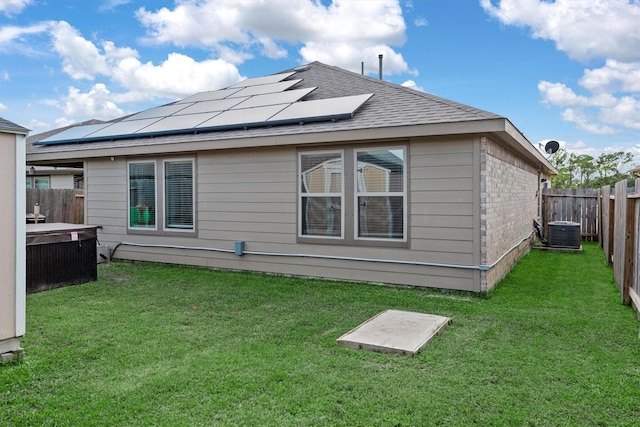 rear view of property featuring a yard, solar panels, and central AC