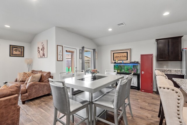 dining room with lofted ceiling and light hardwood / wood-style flooring