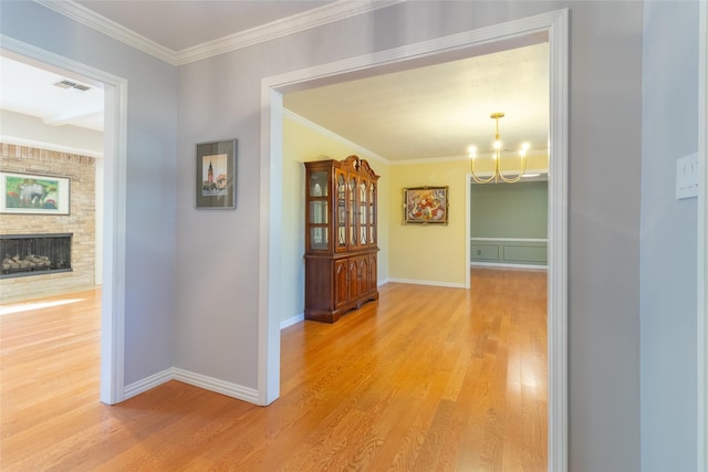 hallway featuring a notable chandelier, ornamental molding, and light hardwood / wood-style floors