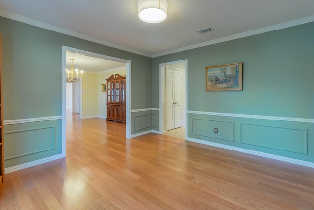 spare room featuring ornamental molding, a chandelier, and light wood-type flooring