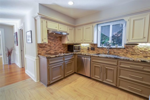 kitchen with dark stone countertops, sink, cream cabinetry, and appliances with stainless steel finishes