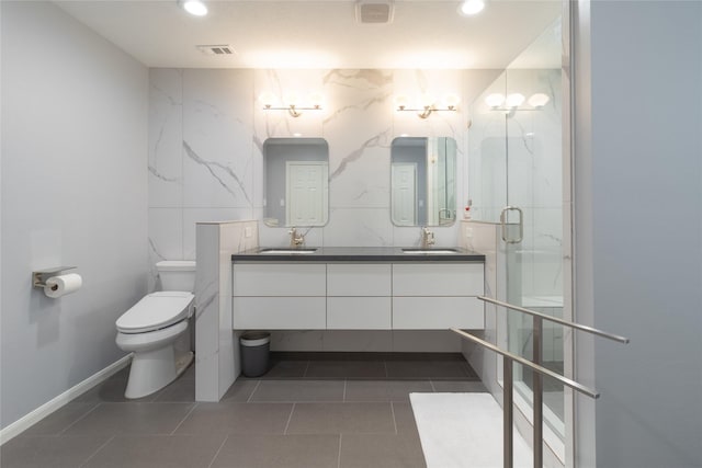 bathroom featuring tile patterned floors, toilet, tile walls, vanity, and a shower with door