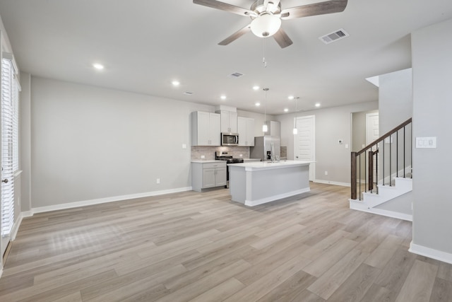 kitchen featuring white cabinetry, light hardwood / wood-style floors, pendant lighting, a kitchen island with sink, and appliances with stainless steel finishes