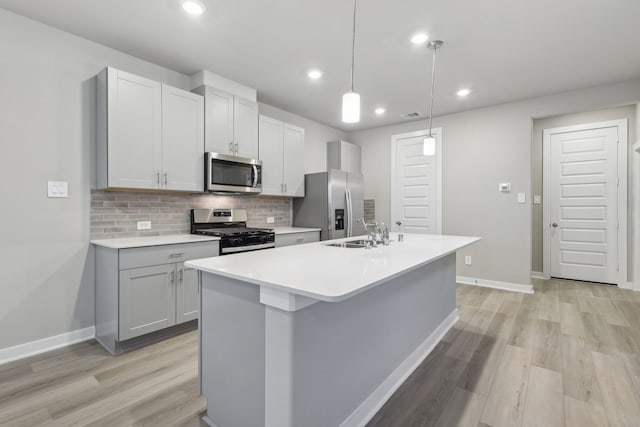 kitchen with pendant lighting, a center island with sink, sink, tasteful backsplash, and stainless steel appliances