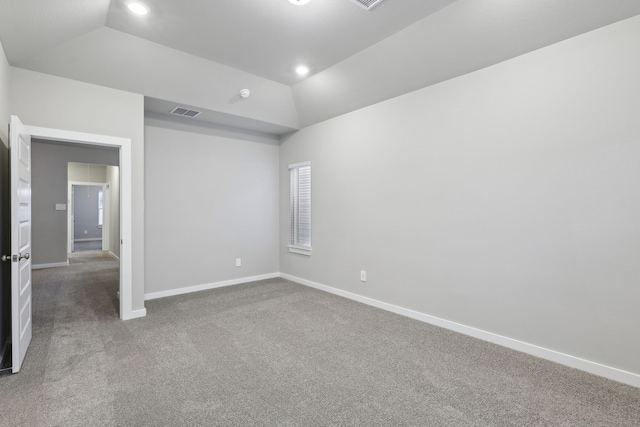 carpeted spare room with vaulted ceiling