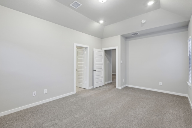 unfurnished bedroom featuring light colored carpet and lofted ceiling