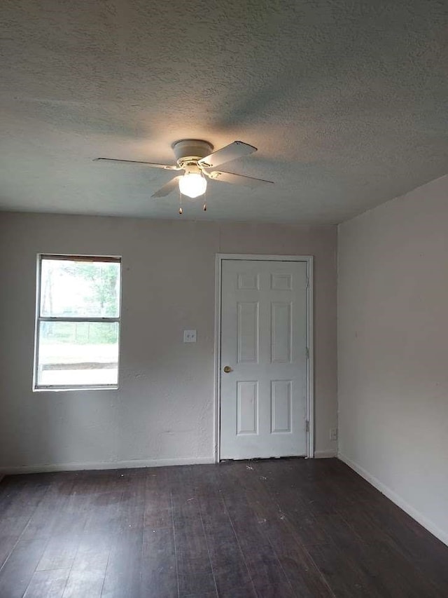 unfurnished room featuring ceiling fan, dark wood-type flooring, and a textured ceiling