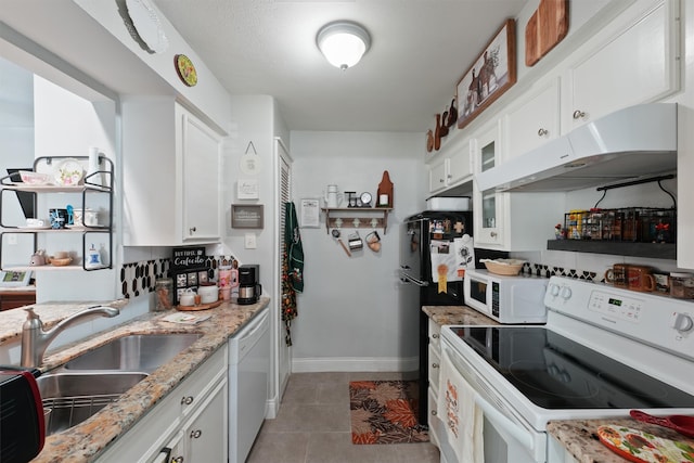 kitchen featuring white appliances, sink, light stone countertops, light tile patterned floors, and white cabinetry