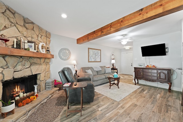 living room with beamed ceiling, light hardwood / wood-style flooring, ceiling fan, and a fireplace