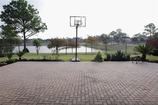 view of patio featuring basketball hoop and a water view