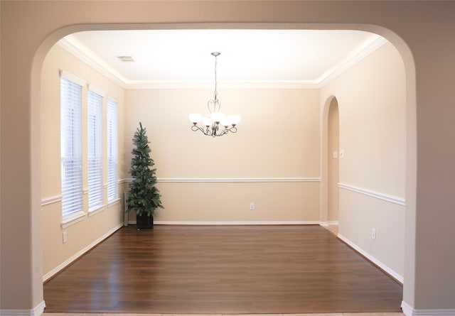 unfurnished dining area with ornamental molding, dark wood-type flooring, and a notable chandelier