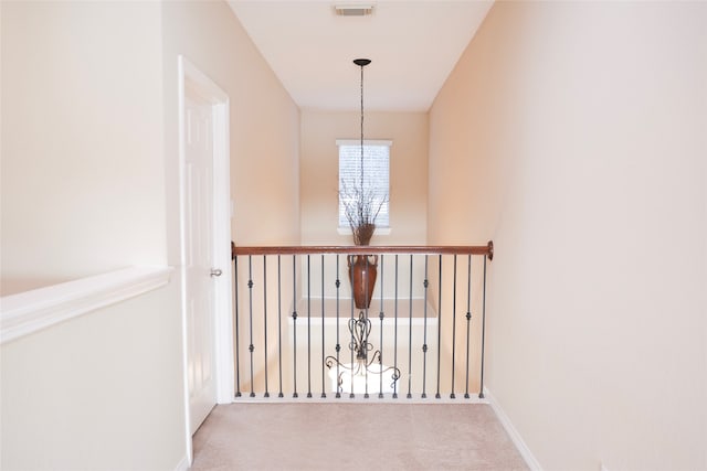 hallway featuring light colored carpet and a notable chandelier