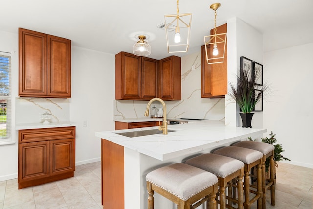 kitchen with a kitchen bar, sink, tasteful backsplash, kitchen peninsula, and pendant lighting