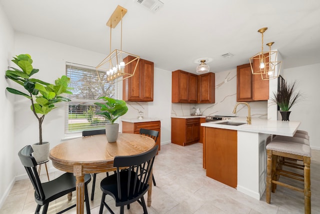 kitchen featuring tasteful backsplash, sink, decorative light fixtures, and kitchen peninsula