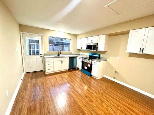 kitchen featuring sink, appliances with stainless steel finishes, light hardwood / wood-style floors, light stone counters, and white cabinetry