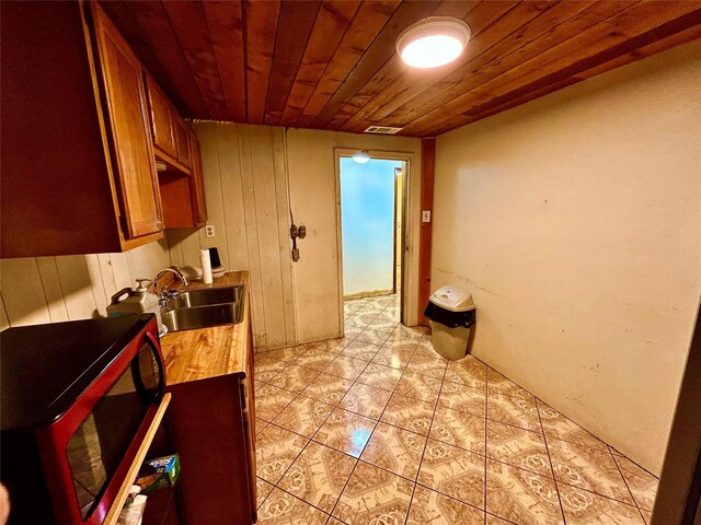 8766 Beauxart Garden Rd, Beaumont, TX 77705 - kitchen featuring a sink, visible vents, brown cabinetry, wooden ceiling, and light tile patterned floors