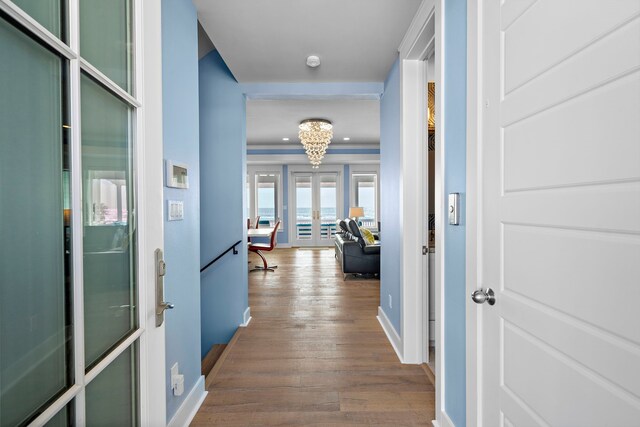 hall featuring ornamental molding, french doors, hardwood / wood-style floors, and a notable chandelier
