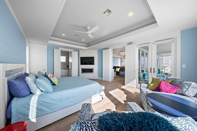 bedroom with a raised ceiling, ceiling fan, and wood-type flooring