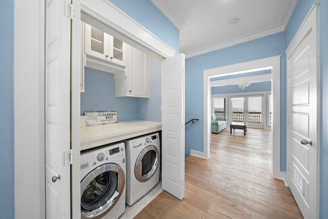 laundry area featuring cabinets, light wood-type flooring, crown molding, washing machine and clothes dryer, and a chandelier