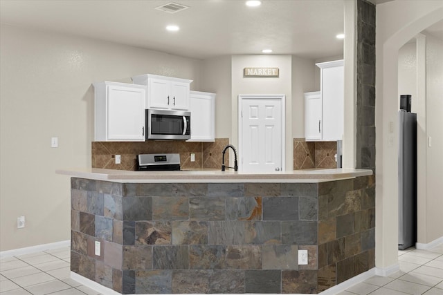 kitchen featuring white cabinetry, stainless steel appliances, light tile patterned flooring, and backsplash