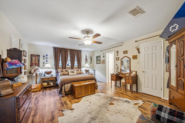 bedroom with hardwood / wood-style flooring, ceiling fan, and a textured ceiling