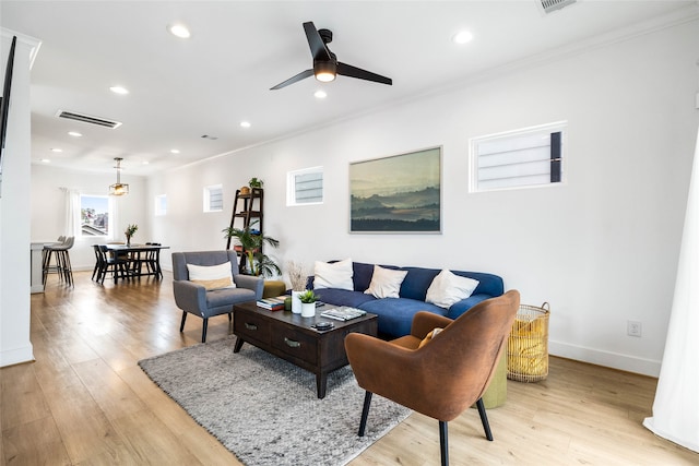 living room with ceiling fan, light wood-type flooring, and crown molding