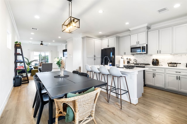 dining space with ceiling fan, light hardwood / wood-style floors, sink, and crown molding