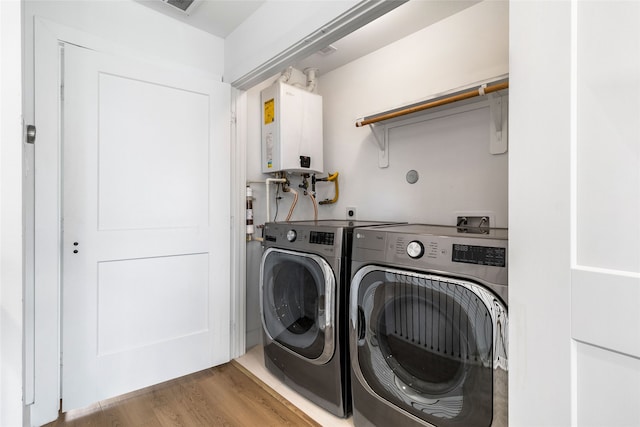 laundry room with hardwood / wood-style floors, washer and clothes dryer, and tankless water heater