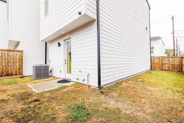 view of side of property featuring central AC unit and a lawn