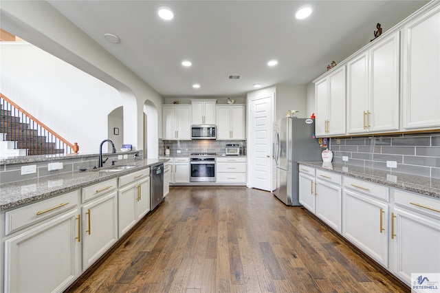 kitchen with light stone countertops, stainless steel appliances, sink, dark hardwood / wood-style floors, and white cabinetry