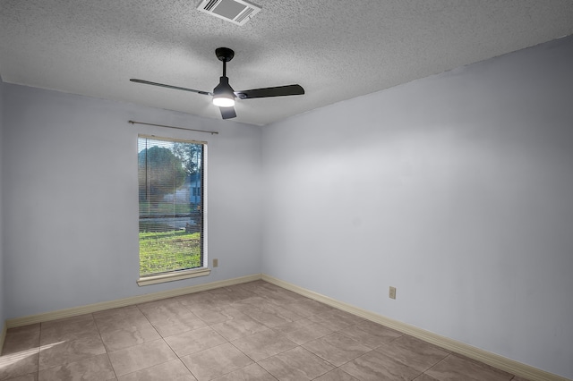 empty room featuring ceiling fan, light tile patterned floors, and a textured ceiling