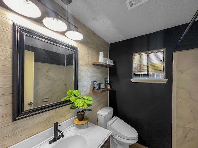 bathroom featuring vanity, toilet, a textured ceiling, and wooden walls