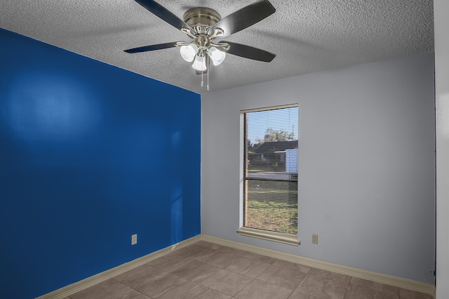 tiled empty room featuring ceiling fan and a textured ceiling