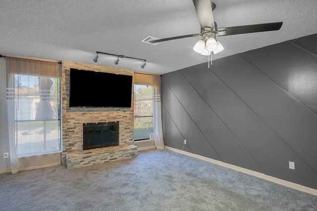 unfurnished living room with carpet flooring, ceiling fan, rail lighting, and a textured ceiling