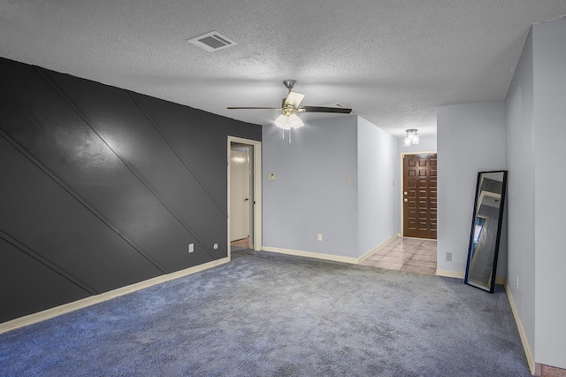 carpeted empty room featuring ceiling fan and a textured ceiling